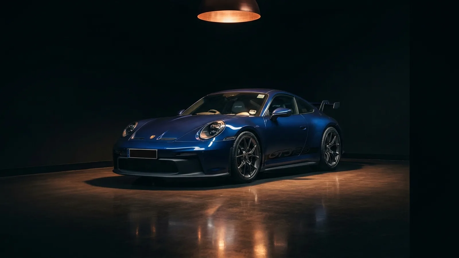 Blauwe Porsche 911 onder een spotlight in een donkere private showroom